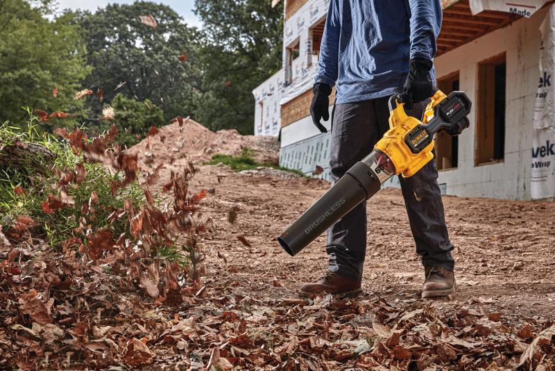 FLEXVOLT Brushless Cordless Handheld Axial Blower being used to clear leaves off  ground